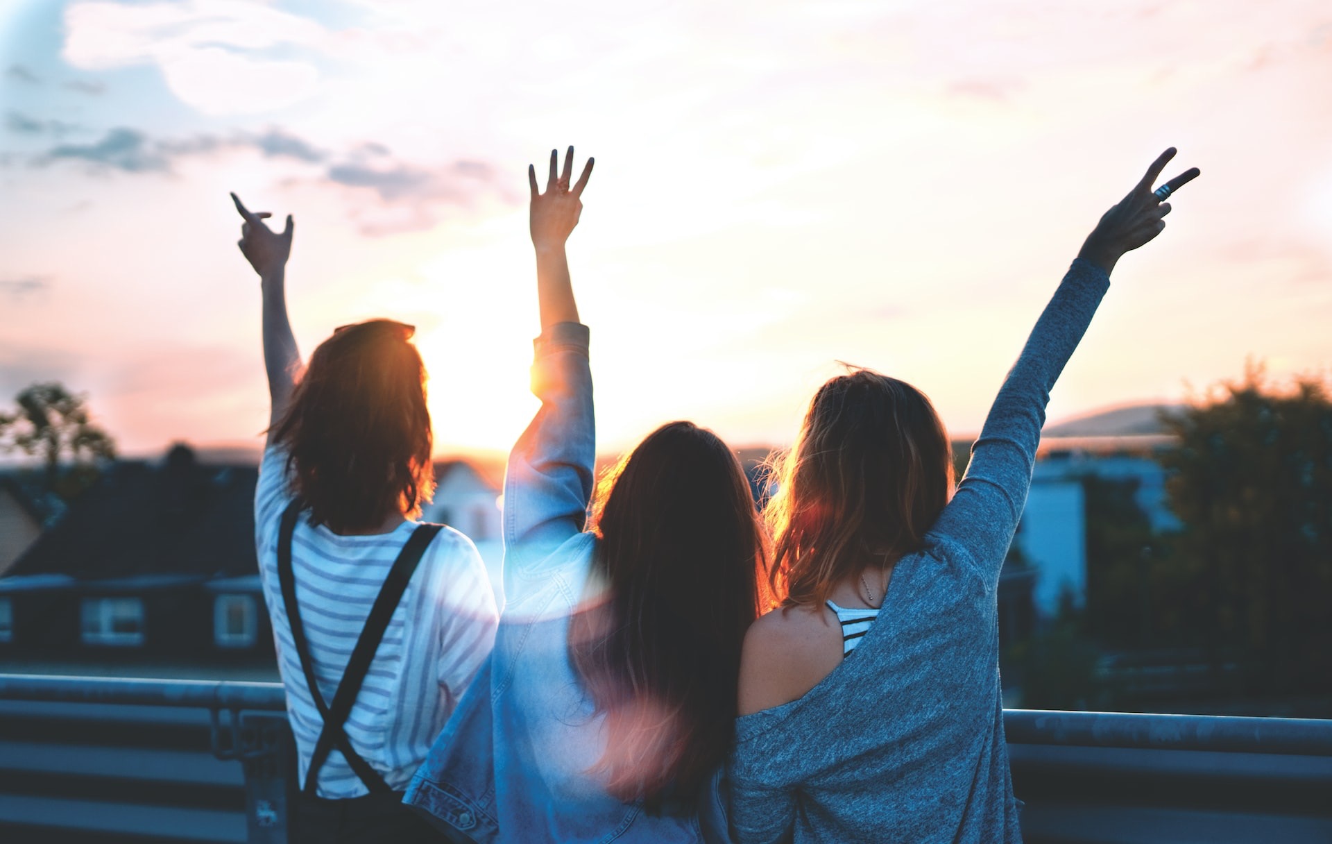 photo of three women lifting there hands \